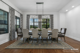 a formal dining room with hardwood floors, large table, lots of windows and a chandelier.