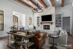 a living room with a stone fireplace, built in bookshelves and lots of natural light.