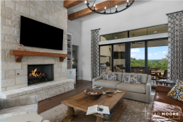 a custom home living room with stone fireplace, large sliding window door to the outdoor living space.