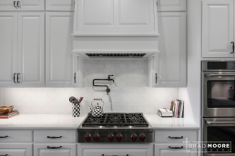 a kitchen with white cabinets, pot filler under cabinet lighting, and stainless steel appliances.
