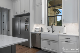 a kitchen with white cabinets, kitchen sink window, large island, and stainless steel appliances