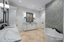 a large master bathroom with tile flooring, designer tile behind the soaking tub, and plenty of countertop space.