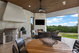 an outdoor kitchen, large stone fireplace, stained wood tongue and groove ceiling with views of the Texas Hill Country.