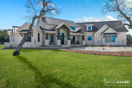 a large white farmhouse custom house with large windows.