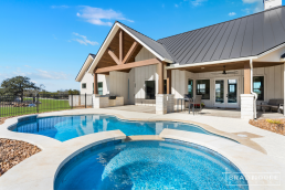 a farmhouse custom home with a pool and patio area.