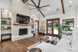 a living room with a stone fireplace and wood floors and french doors leading to outdoor patio.