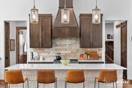 a custom home kitchen with a center island, backsplash behind cooktop and four chairs