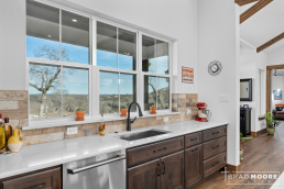 a custom home kitchen with dark wood cabinets, undercounter sink, and wood floors