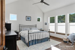 a primary master bedroom with a bed, multiple windows and a ceiling fan