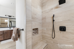 a master bath walk-in shower with a shower head and soap nook.